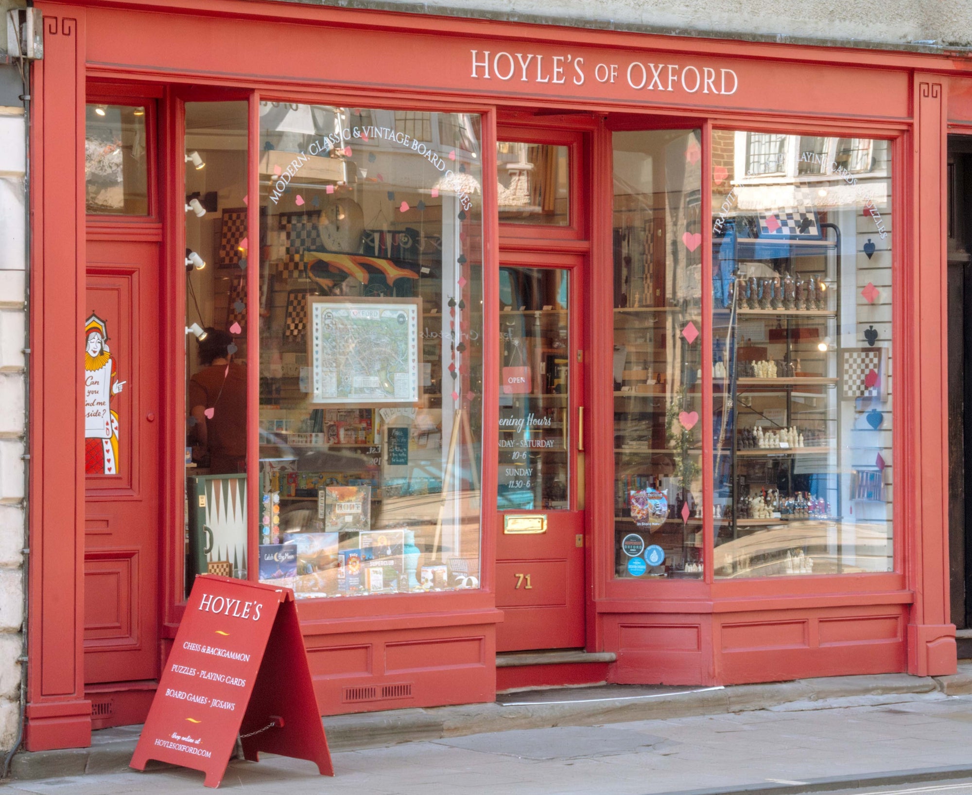 Red store front of Hoyle's of Oxford with glass windows and a sign outside.