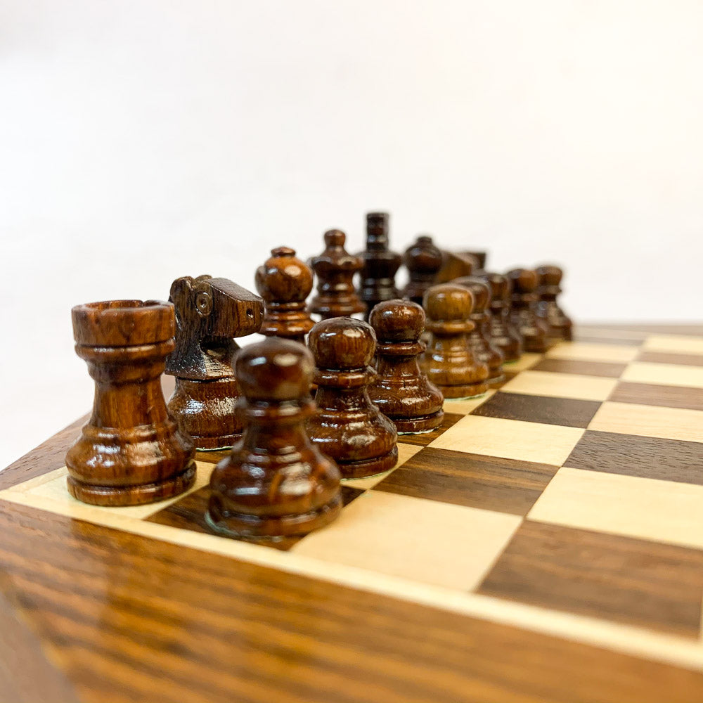 Dark chess pieces laid out on wooden board ready for play.
