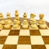 Light wooden chess pieces laid out ready for a game on wooden board.
